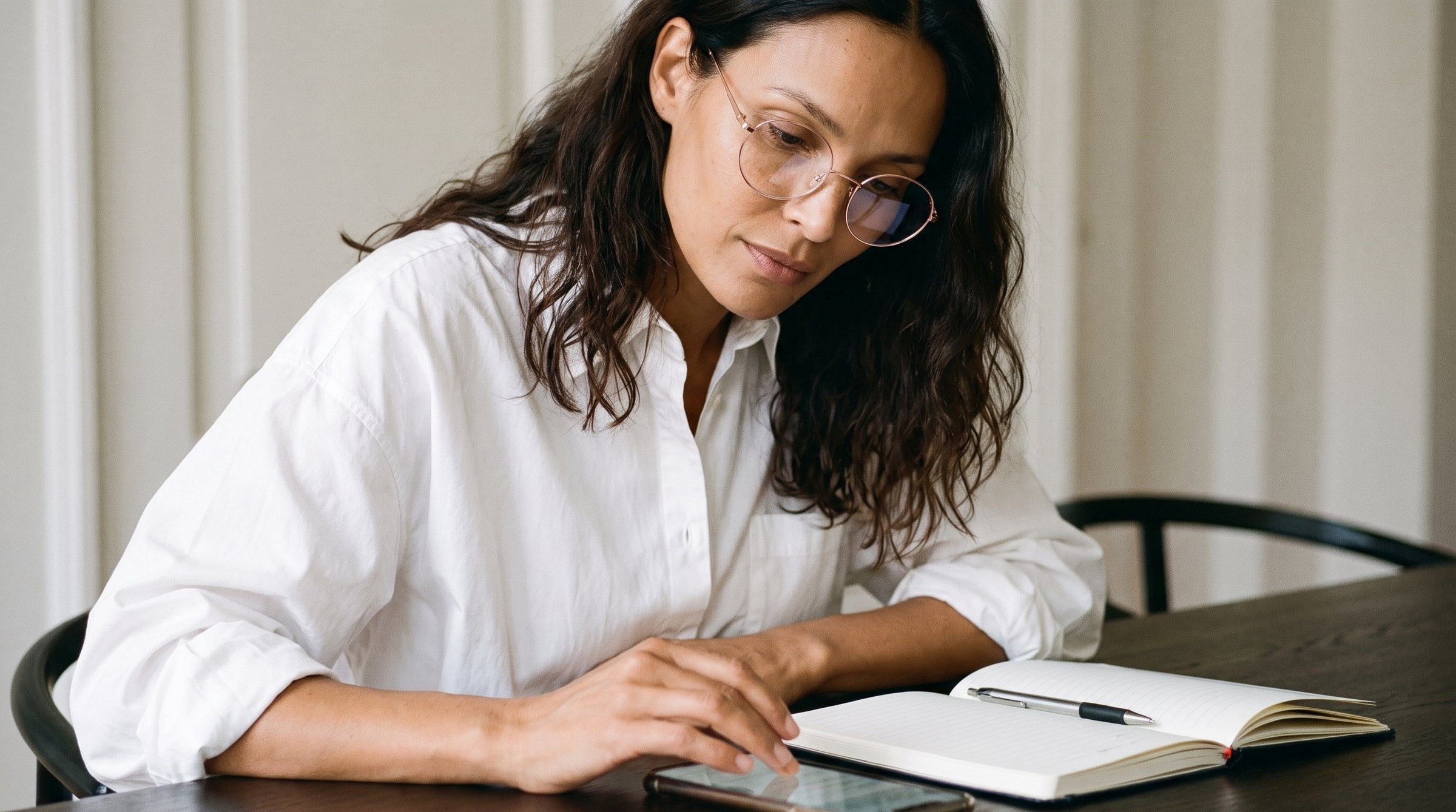Woman reading at a table wearing Grace Rose Gold Blue Light glasses